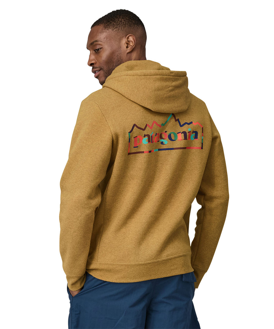 A man wearing a Patagonia Unity Fitz Uprisal Hoody in a yellow colour stood in front of a plain background. The man is facing away from the camera, showing the back of the top. 