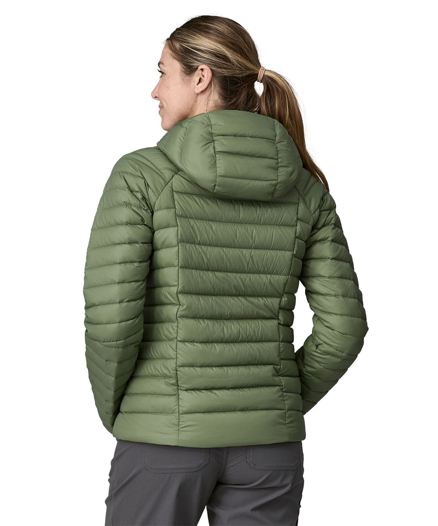 A woman wearing a Patagonia Women's Down Sweater Hoody in terrain green, facing away showing the back of the coat.