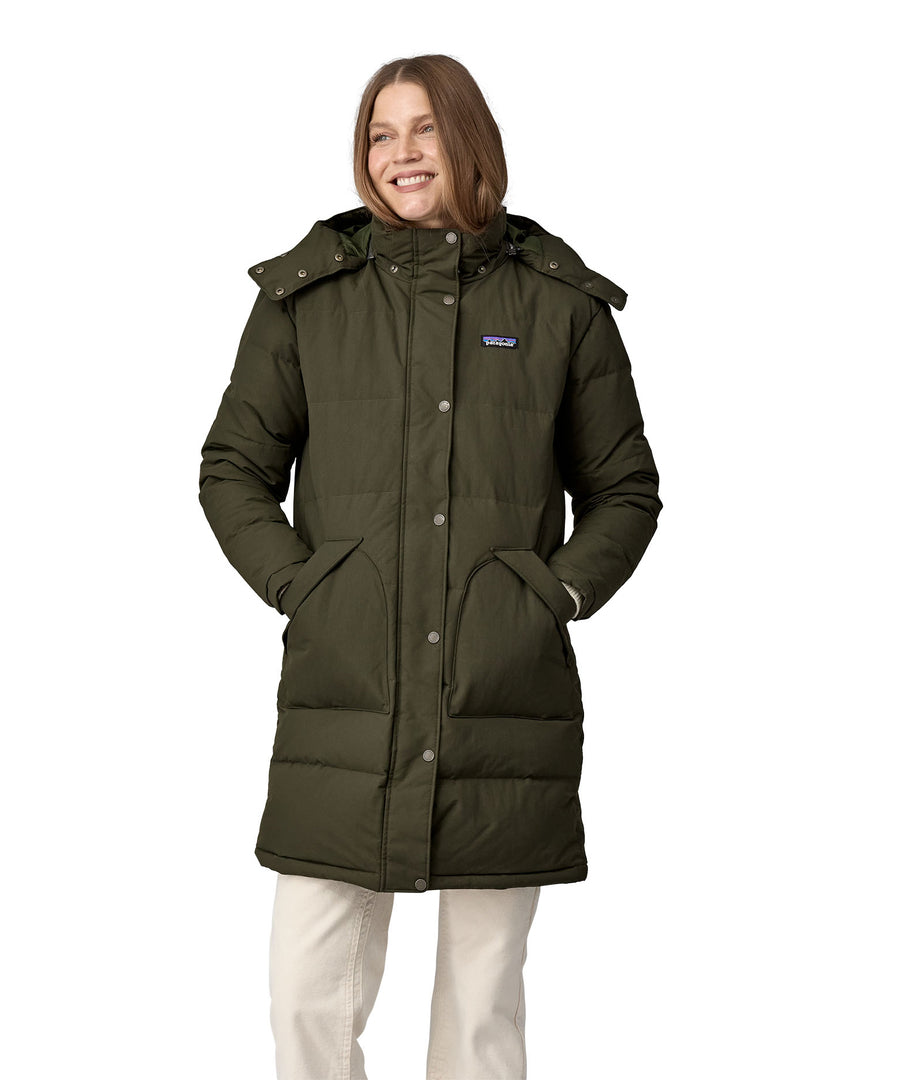 A woman wearing the Patagonia Women's Downdrift Parka in Pine Needle Green. The zip is fully closed