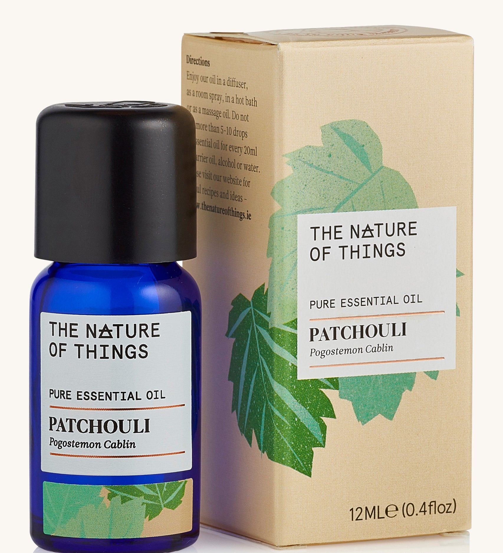 Patchouli pure essential oil in a blue glass bottle in front of a decorative cream cardboard box.