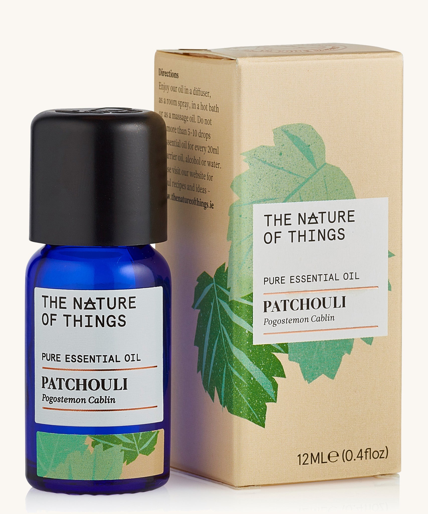 Patchouli pure essential oil in a blue glass bottle in front of a decorative cream cardboard box.