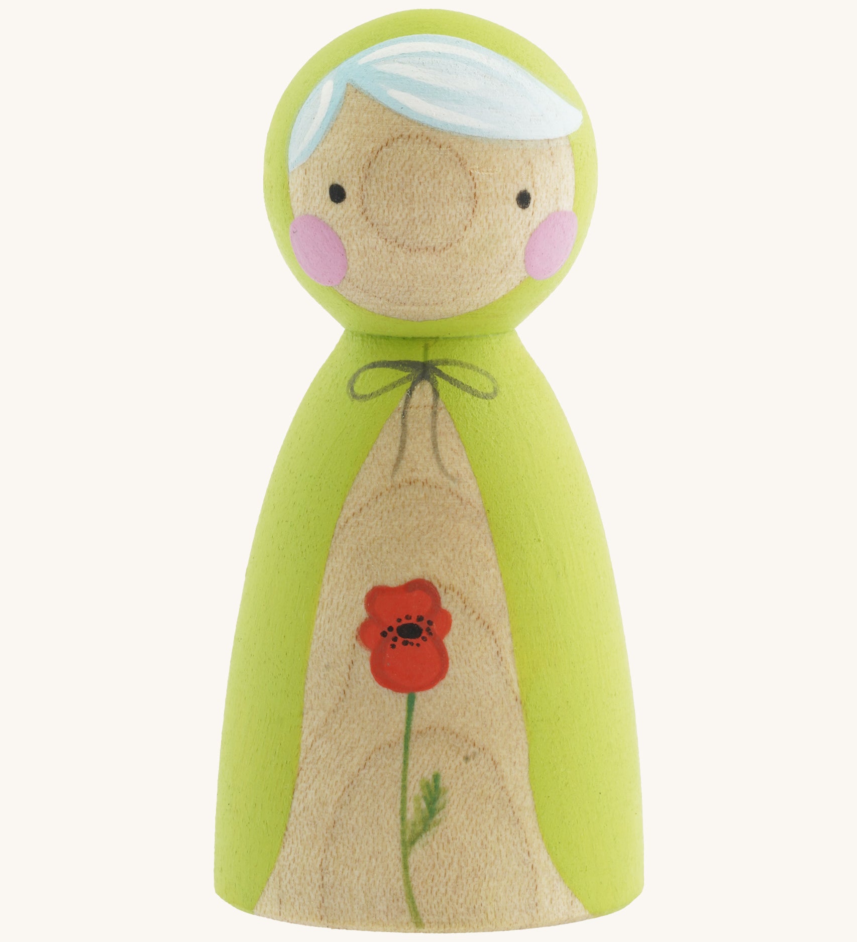 A wooden handmade Peepul peg doll wearing a light green cape with a red poppy painted on the front on cream background.