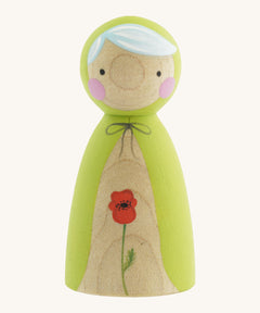 A wooden handmade Peepul peg doll wearing a light green cape with a red poppy painted on the front on cream background.