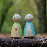 two hand painted peg dolls, one with a white poppy painted on its front, the other with a red poppy