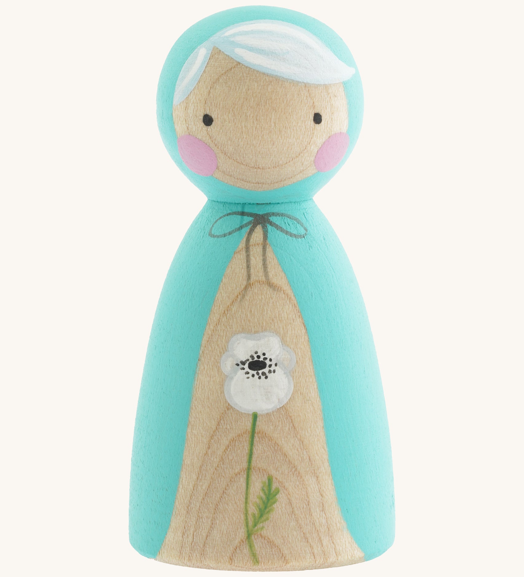 A wooden handmade Peepul peg doll wearing a light blue cape with a white poppy painted on the front on cream background.