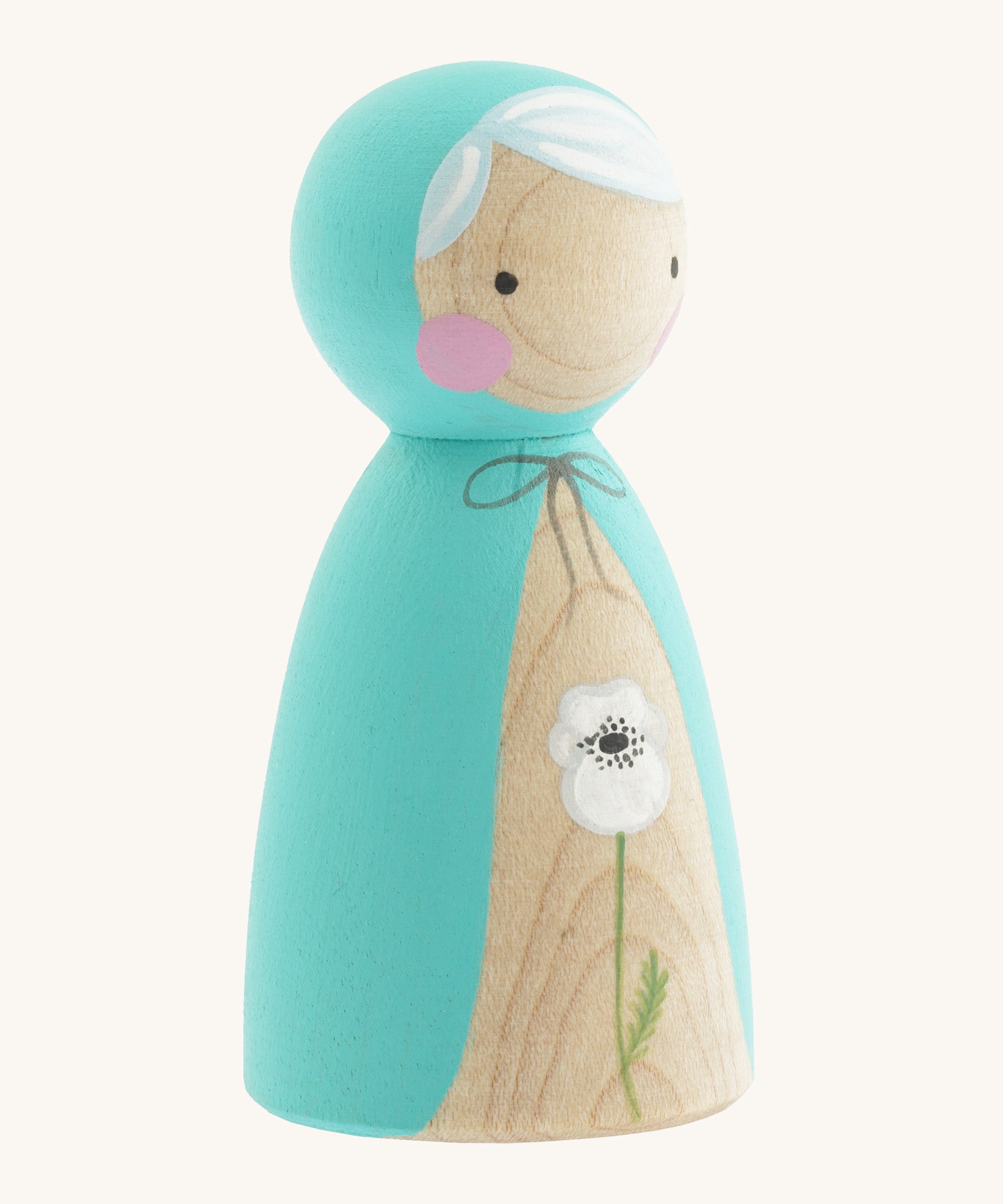 A side photo of the wooden handmade Peepul peg doll wearing a light blue cape with a white poppy painted on the front on cream background.