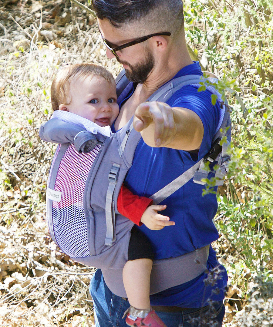 An adult carrying a baby in the Love Radius PhysioCarrier in Elephant.