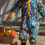 Young boy sat on some stone steps wearing the multicoloured Piccalilly organic cotton hooded playsuit