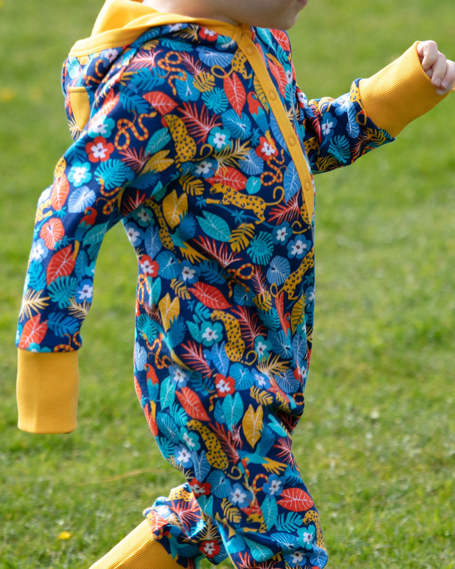  wearing the Piccalilly organic cotton hooded playsuit in the multicoloured tropical print