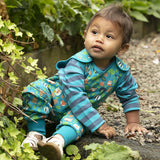 Young boy sat on some stones wearing the Piccalilly organic cotton dungarees in the tree tops print