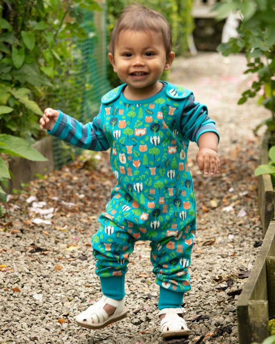 Young boy walking on some gravel wearing the Piccalilly kids organic cotton tree tops dungarees