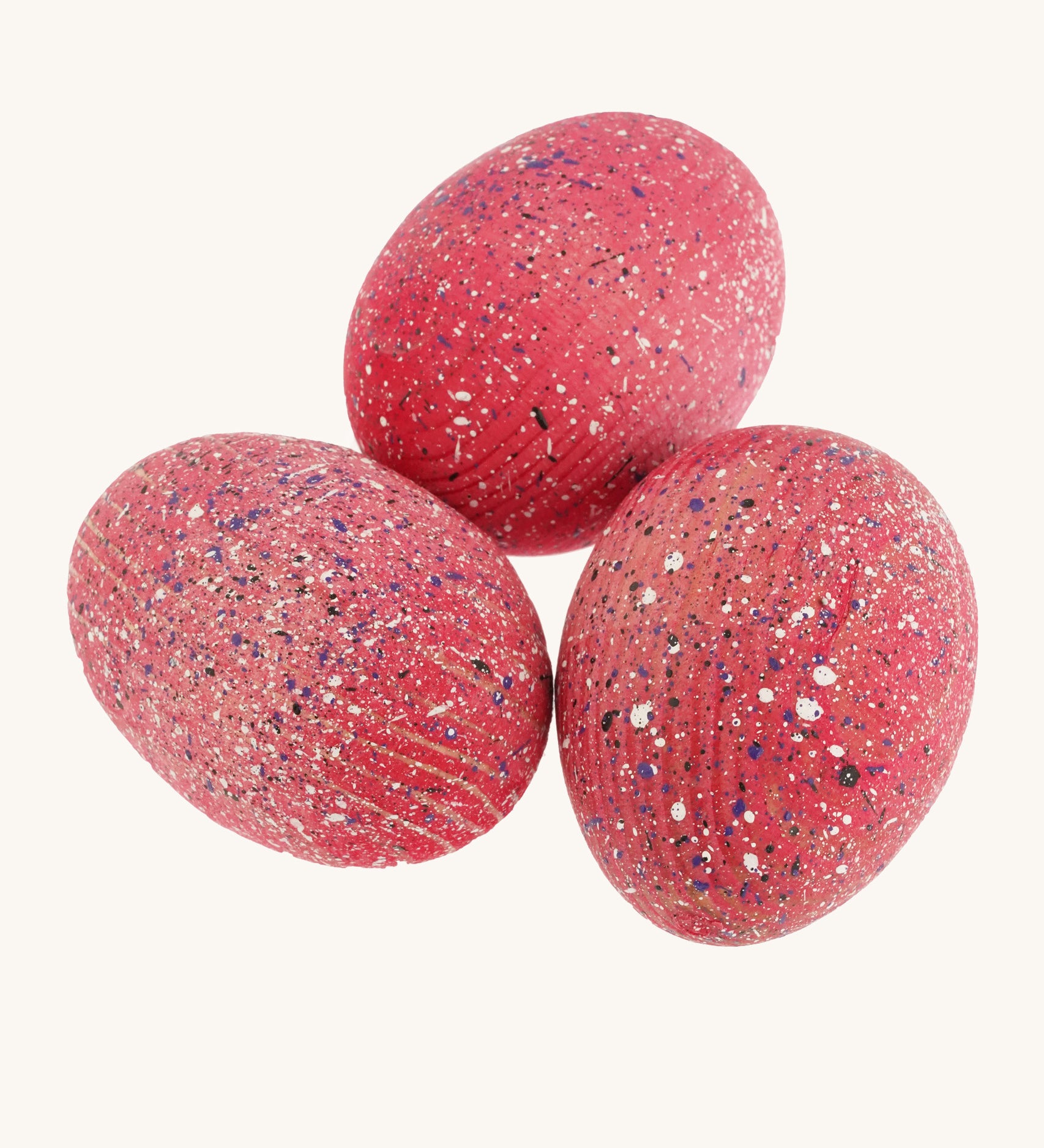 3 wooden speckled pink dinosaur eggs on a cream background