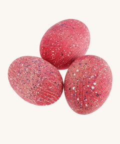 3 wooden speckled pink dinosaur eggs on a cream background