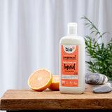 Bio-D vegan friendly Pink Grapefruit scented Washing Up Liquid in a 750ml bottle on a wooden table with cut grapefruits