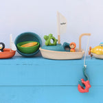 A collection of PlanToys wooden bath toys on a blue painted surface. 