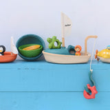 A collection of PlanToys wooden bath toys on a blue painted surface. 