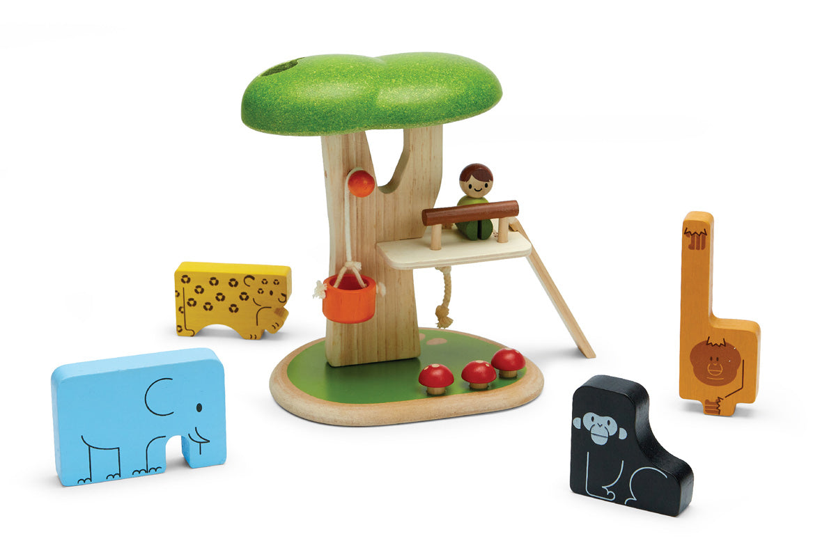 Plan Toys childrens stacking wooden animal jigsaw pieces laid out on a white background next to a plan toys tree house play set on a white background