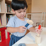 Boy stood at a table playing with the Plan Toys wooden chisel and mallet toy