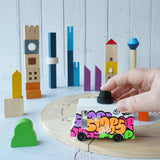 The PlanToys Wooden Cityscape Blocks set up in a play scene with the PlanToys wooden road and a Candylab graffiti van. 