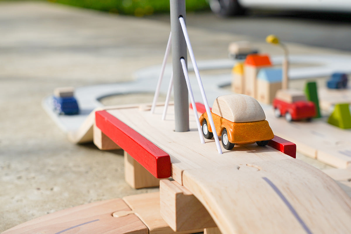 Close up of Plan Toys car on top of the Plan Toys Wooden road set