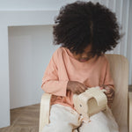 A child sitting down holding the PlanToys Elephant Money Bank.