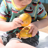 A child playing with the small yellow bowl from the PlanToys Fountain Bowl Set they are pouring water into a yellow PlanToys submarine. 