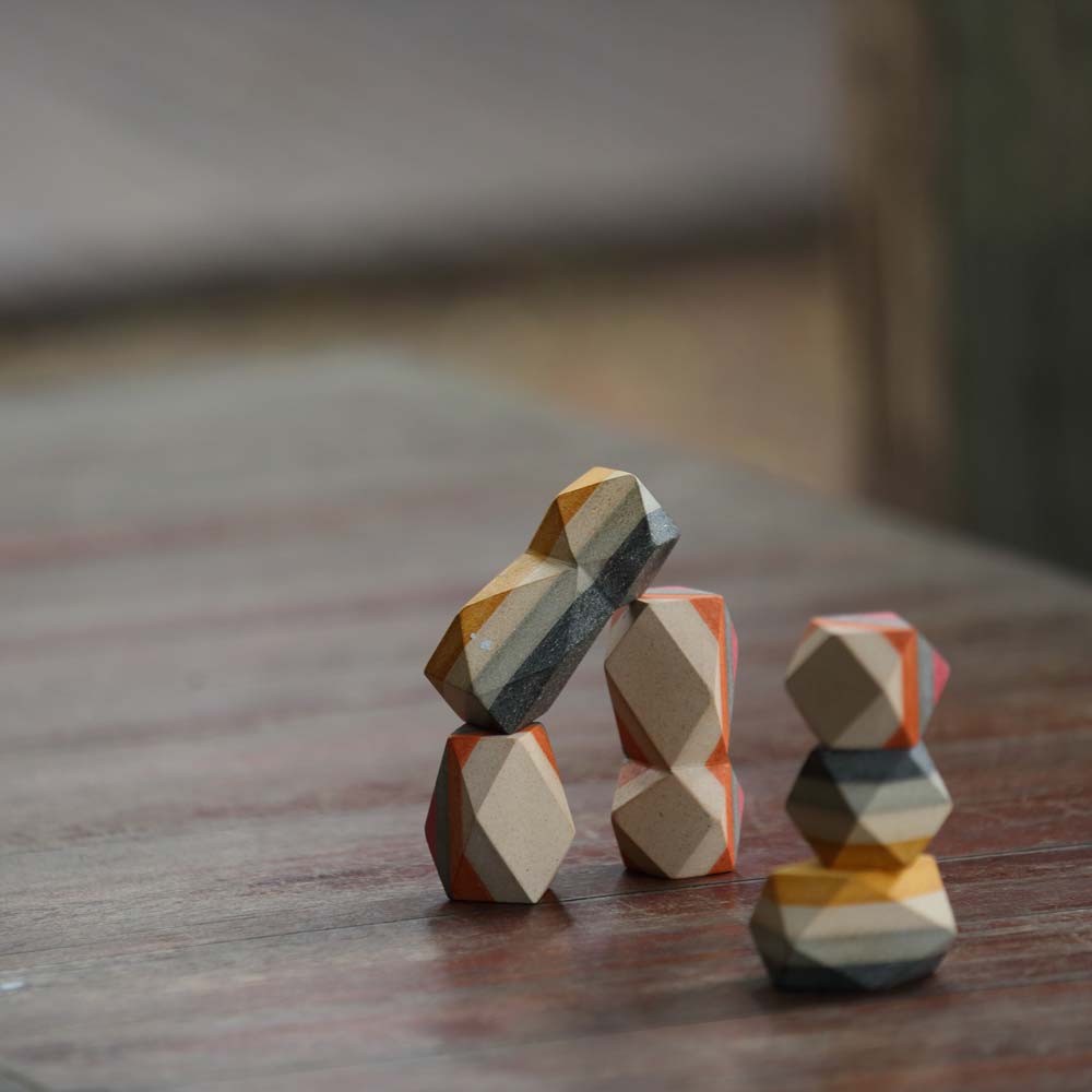 The PlanToys Geo Stacking Rocks placed on a dark wooden surface.