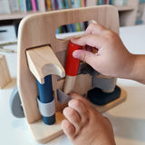 Close up of a hand pulling out a tool from the Plan Toys plastic free wooden carpenter role play toy set