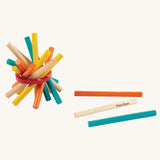 A bundle of sticks from the PlanToys Mini Pick-Up Sticks on a plain background with three of the sticks placed besides the bundle. 