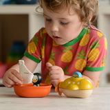 A child playing with a Plan Toys Penguin Sailing Boat. 