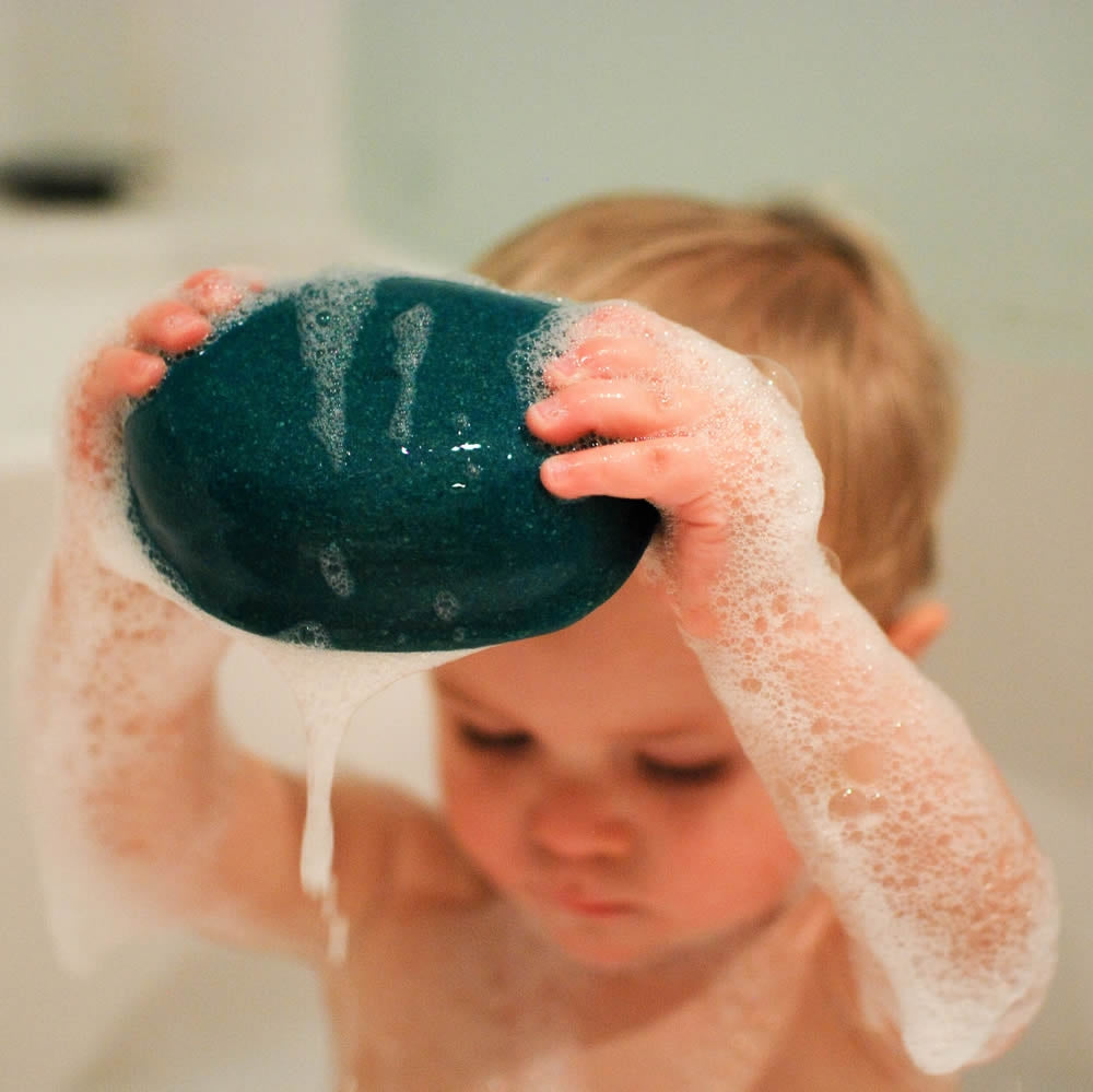 A playing with Plan Toys Polar Bear Sailing Boat in the bath. The boat is covered in soapy suds. 