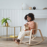 A child sitting on a PlanToys children's Rocking Chair. 