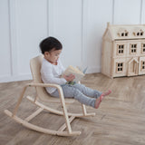 A child sitting on a PlanToys children's Rocking Chair. 