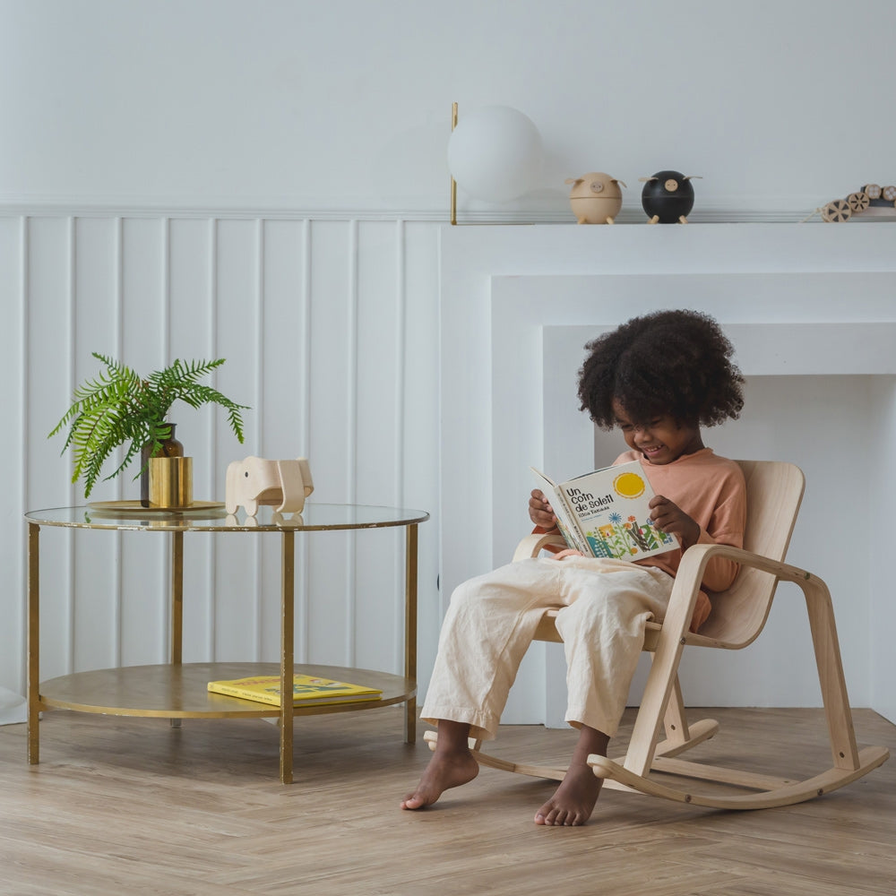 A child sitting on a PlanToys children's Rocking Chair. 