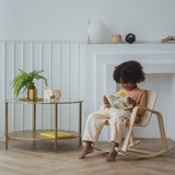 A child sitting on a PlanToys children's Rocking Chair. 