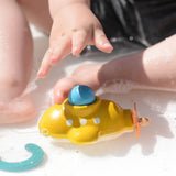 A child playing with the PlanToys submarine bath toy in shallow water. 