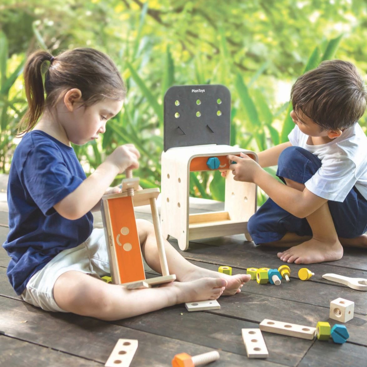 Two children sat playing with the PlanToys Workbench. 