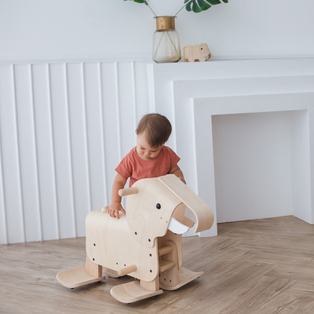 A child standing by the side of a PlanToys Walking Elephant. 