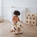 A child riding on a PlanToys Walking Elephant, one side of the elephant is raised from the floor in motion. 