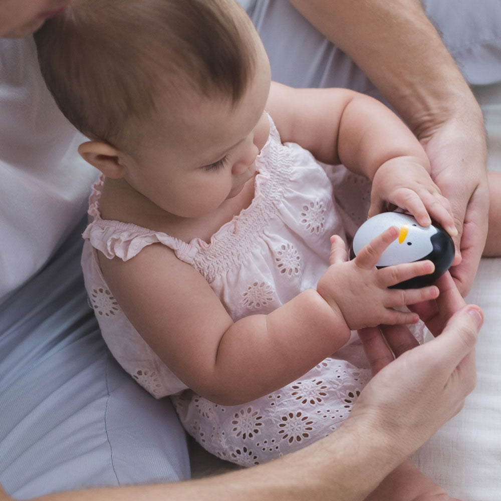 A baby playing with the PlanToys wobbly penguin toy. 