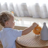 A child putting a coin in the PlanToys Yellow Piggy Bank.
