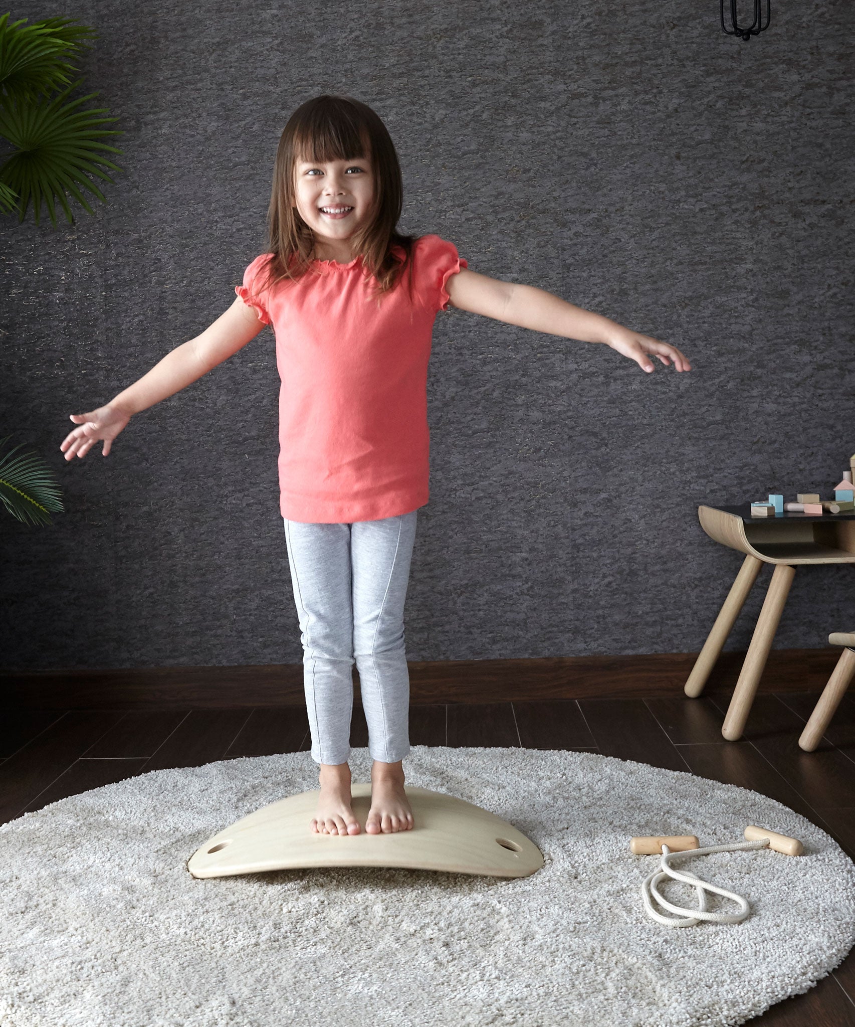 A child standing on an upturned PlanToys Balance Board. The board upturned creates a sort of mini bridge for the child to stand upon. 