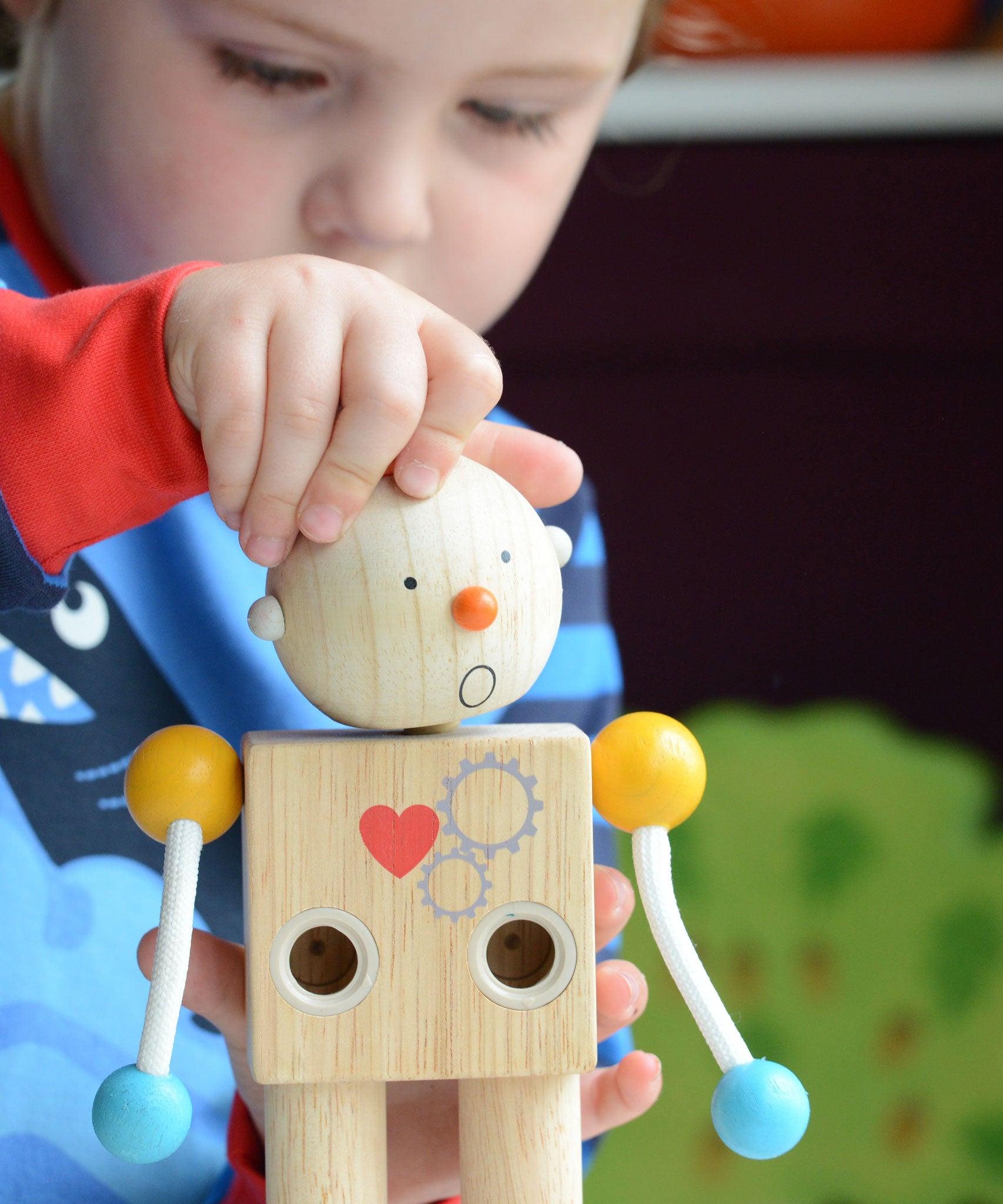 A child placing the round shocked expression head on the PlanToys Build a Robot toy. 