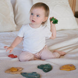 A child sitting on a bed playing with the PlanToys Marine Puzzle.