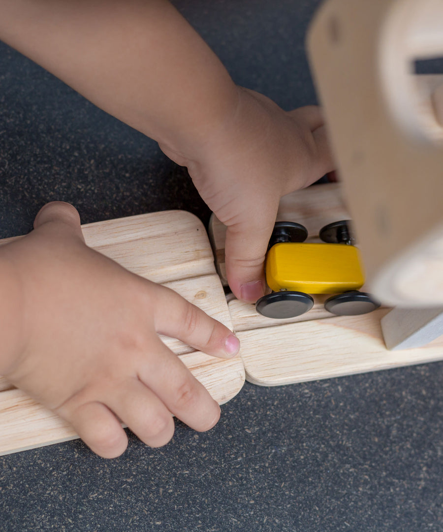 A close up of a child attaching a piece of the track to the PlanToys Ramp Racer. 