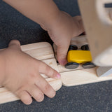 A close up of a child attaching a piece of the track to the PlanToys Ramp Racer. 