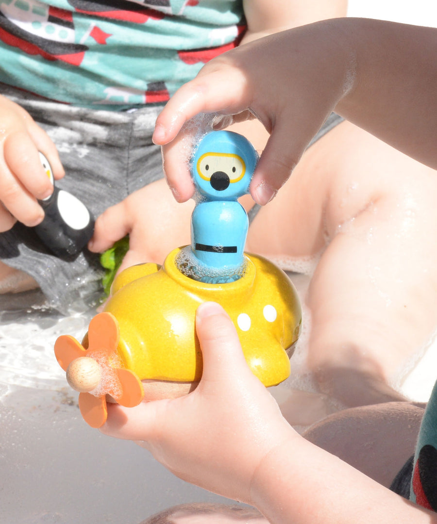 A close up of a child playing with the PlanToys Submarine Bath Toy placing the diver inside. 