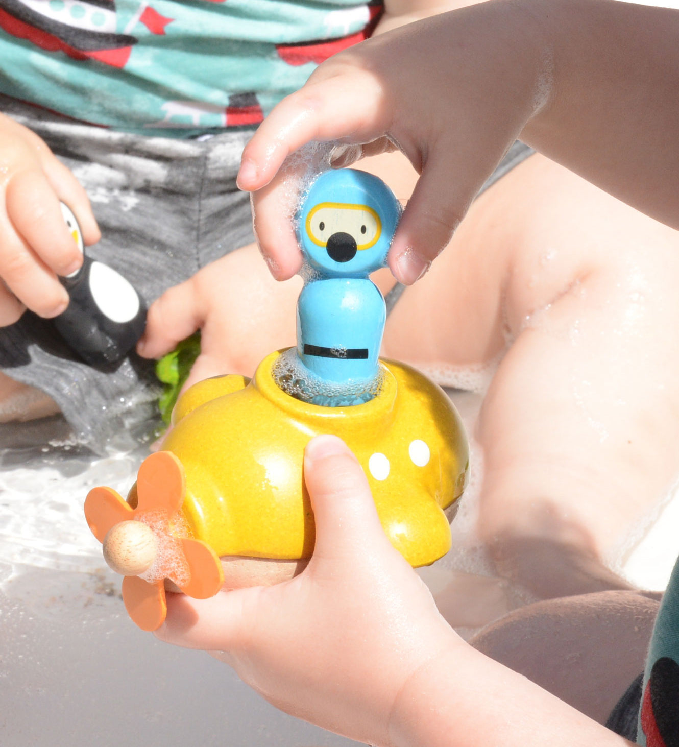 A close up of a child playing with the PlanToys Submarine Bath Toy placing the diver inside. 