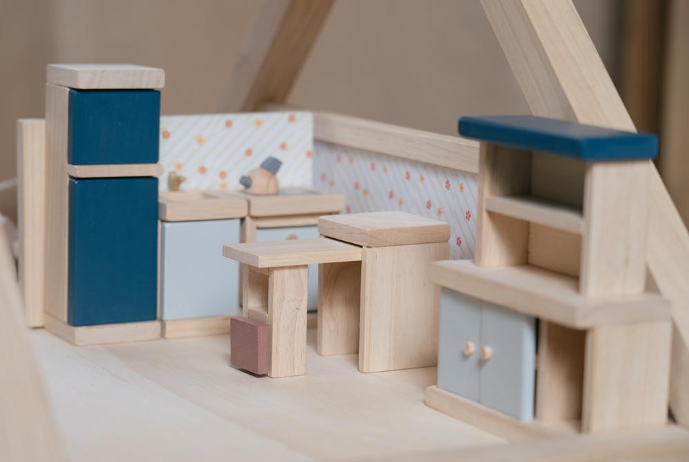 The PlanToys Kitchen Dolls House Furniture set placed in a wooden dolls house. 
