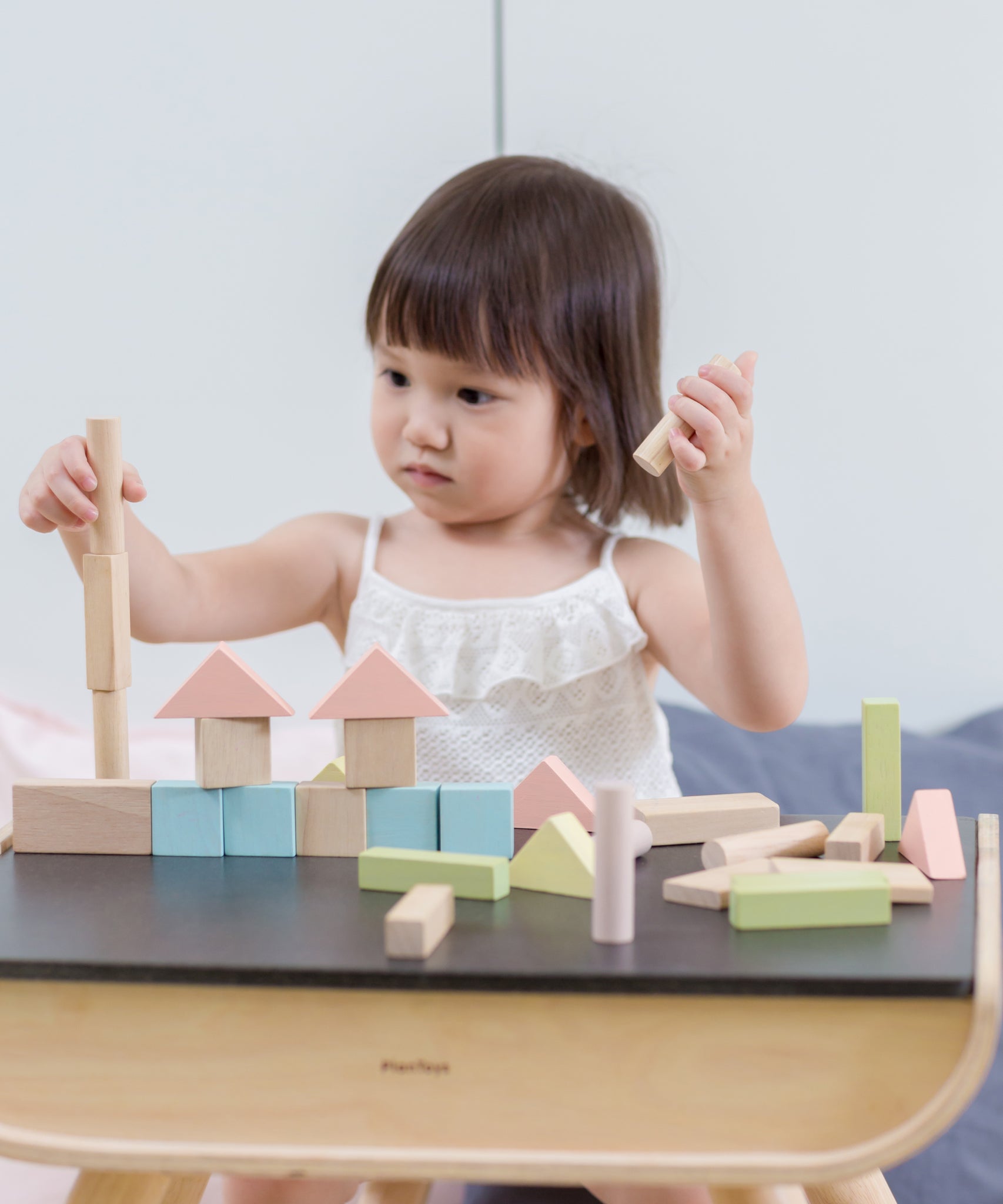 A child playing with the PlanToys Pastel Blocks set on a PlanToys desk. 